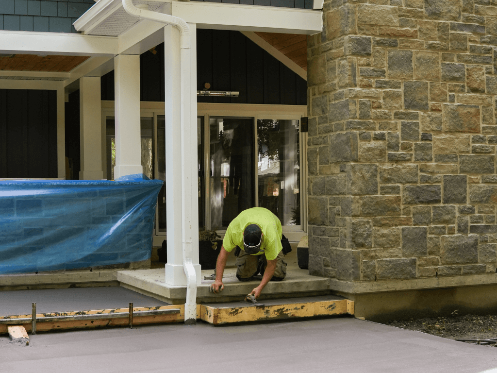 Brosco Concrete crew placing and finishing concrete: worker at house entry with stone