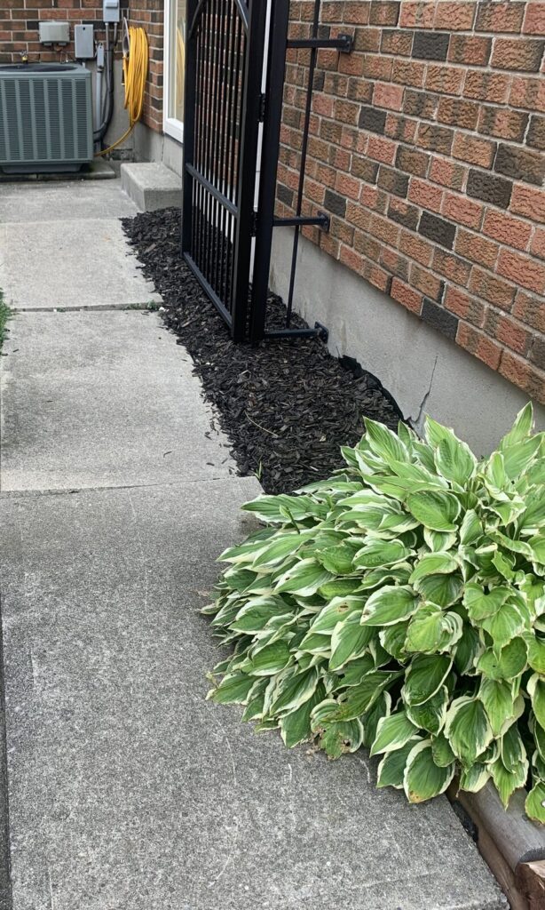 Settled concrete walkway beside a house before levelling